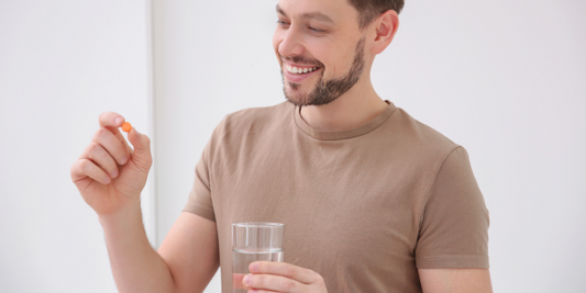 Man holding a vitamin tablet smiling